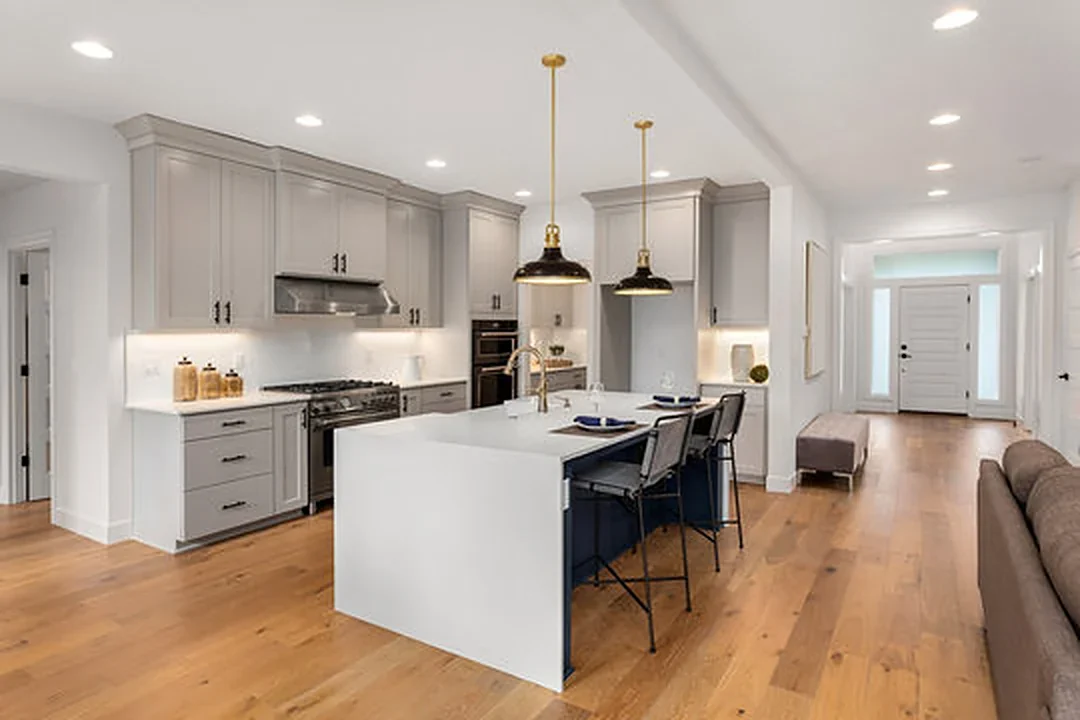 Open-plan kitchen with grey shaker cabinets, white waterfall island and navy island base — tap a swatch to change the finishes